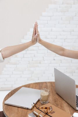 Two girls high-fiving each other over a desk
