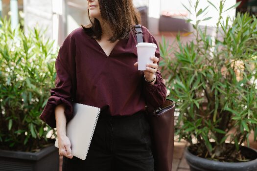 woman holding coffee cup and computer