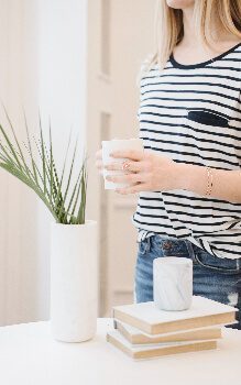 A girl wearing a blue and white striped shirt standing up at her desk