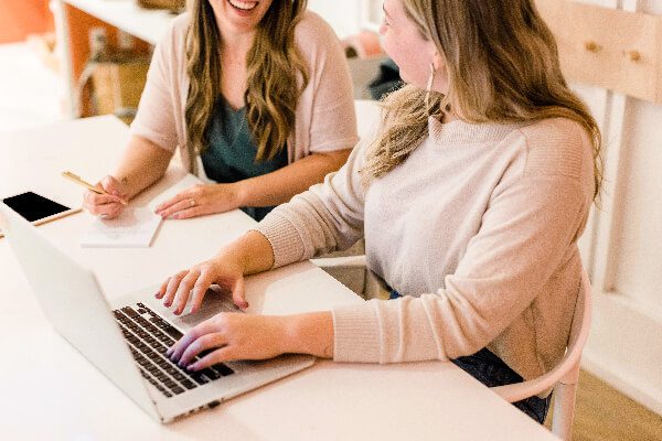 Two girls sitting at a desk, working on computers