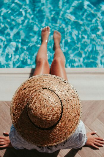 A woman sitting on the side of a pool with her legs in the water